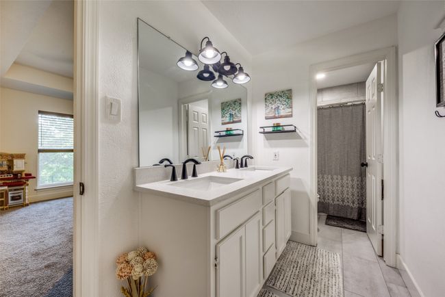 Bathroom featuring baseboards, double vanity, a shower with shower curtain, and tile patterned floors | Image 17