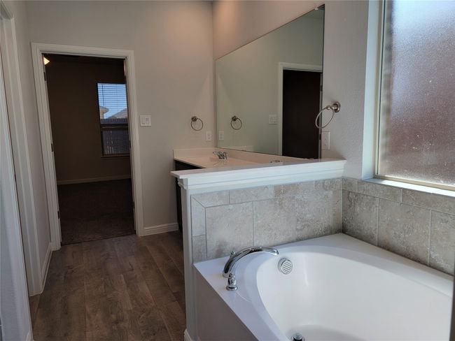 Bathroom featuring a garden tub, wood finished floors, a sink, and baseboards | Image 16