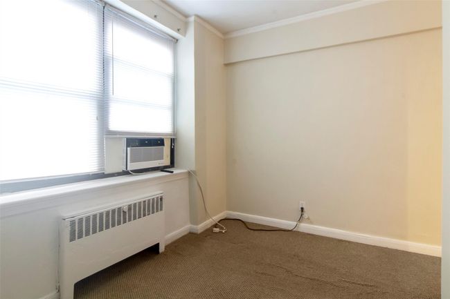 Carpeted empty bedroom alcove featuring radiator, crown molding, and cooling unit | Image 11
