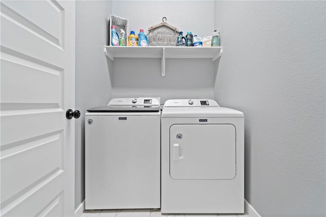 Clothes washing area featuring a textured wall, washer and clothes dryer, and laundry area | Image 10
