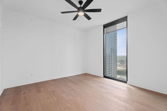 Spare room with expansive windows, light wood-style flooring, and ceiling fan | Image 14