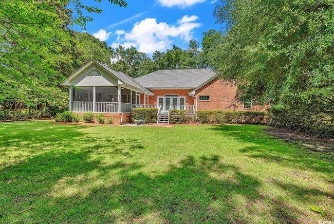 Rear view of house featuring a sunroom, brick siding, a lawn, a wooden deck, and french doors | Image 33