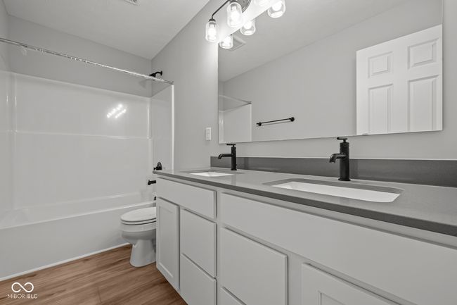 full bathroom featuring toilet, a sink, double vanity, and wood finished floors | Image 15