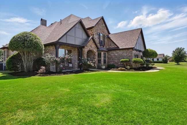 Tudor house with brick siding, a front lawn, roof with shingles, and a chimney | Image 4