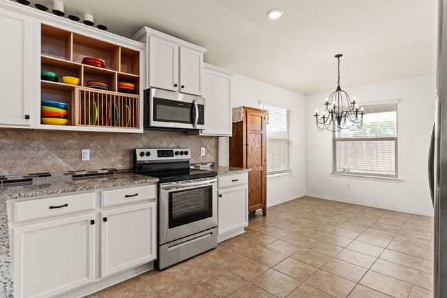 Kitchen with open shelves, appliances with stainless steel finishes, a chandelier, white cabinetry, and decorative backsplash | Image 8