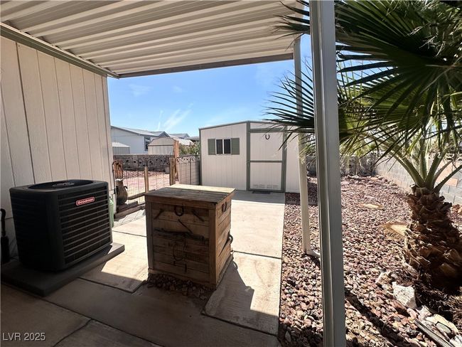 View of patio / terrace with a storage unit, a fenced backyard, central air condition unit, and an outbuilding | Image 22