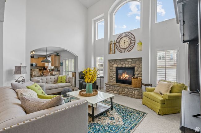Living room featuring carpet flooring, arched walkways, a high ceiling, and a fireplace | Image 12