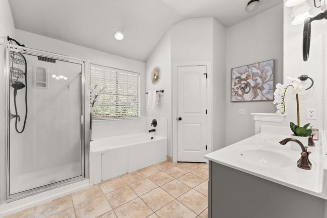 Bathroom featuring a stall shower, a bath, lofted ceiling, double vanity, and tile patterned flooring | Image 15