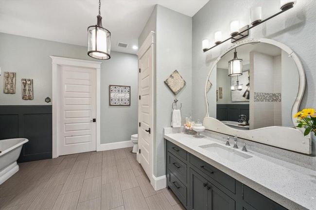 The in-law suite’s primary bathroom boasts custom cabinetry, sleek quartz countertops, and stunning tile accents with a custom design. Crown molding adds a touch of elegance, creating a sophisticated and functional space that feels both luxurious and practical. | Image 39