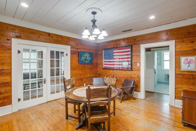 Dining space with french doors, wooden walls, a chandelier, light wood finished floors, and crown molding | Image 18
