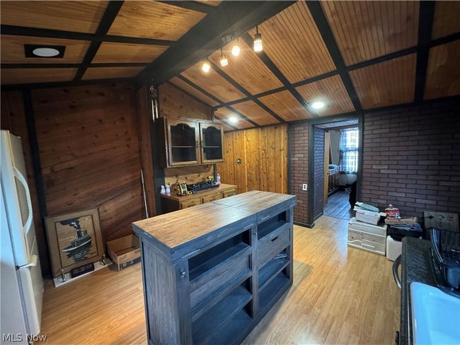 Kitchen with vaulted ceiling with beams, white refrigerator, light hardwood / wood-style flooring, wooden counters, and wood walls | Image 10