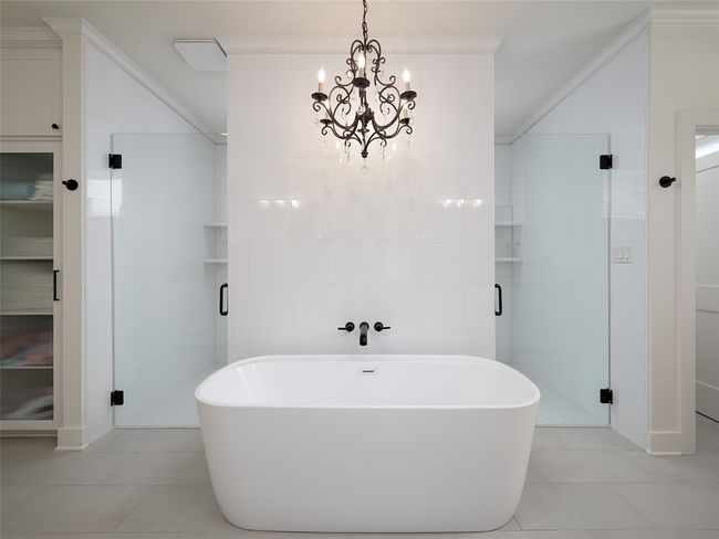 Bathroom featuring tile patterned floors, ornamental molding, a freestanding bath, a shower stall, and tile walls | Image 18