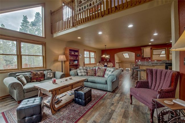 Living area featuring wood finished floors, arched walkways, recessed lighting, a chandelier, and a high ceiling | Image 9