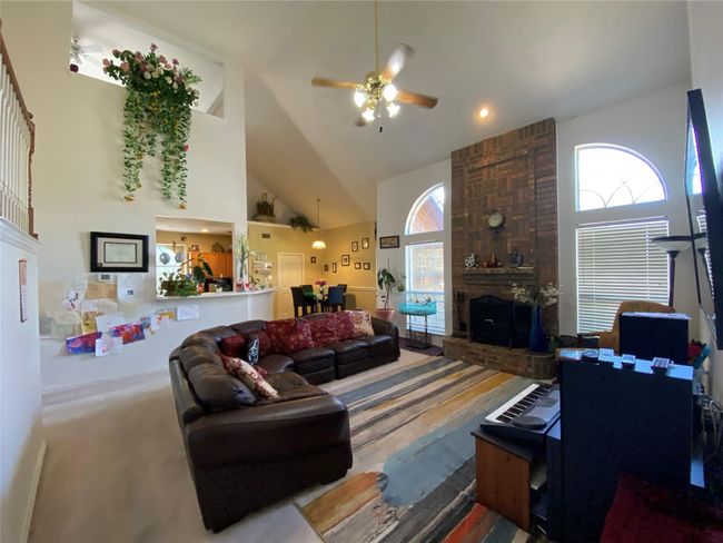 Carpeted living room featuring a brick fireplace, high vaulted ceiling, and ceiling fan | Image 15