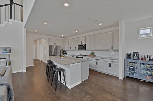 Kitchen featuring a kitchen bar, dark wood-style flooring, arched walkways, visible vents, and appliances with stainless steel finishes | Image 8