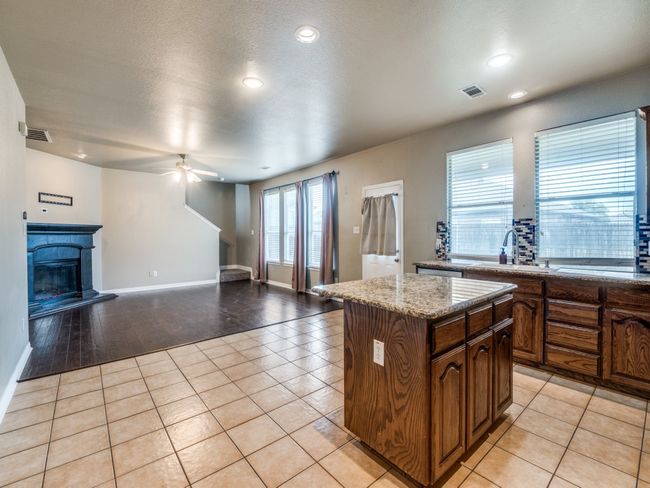Kitchen with light tile patterned flooring, ceiling fan, visible vents, a kitchen island, and open floor plan | Image 10