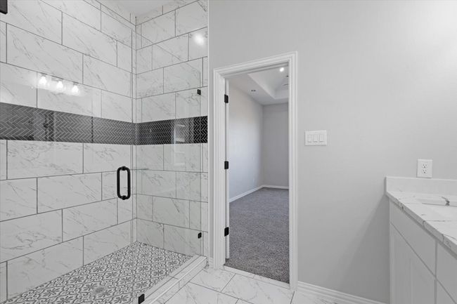 Bathroom featuring marble look tiles, a shower stall, and vanity | Image 22