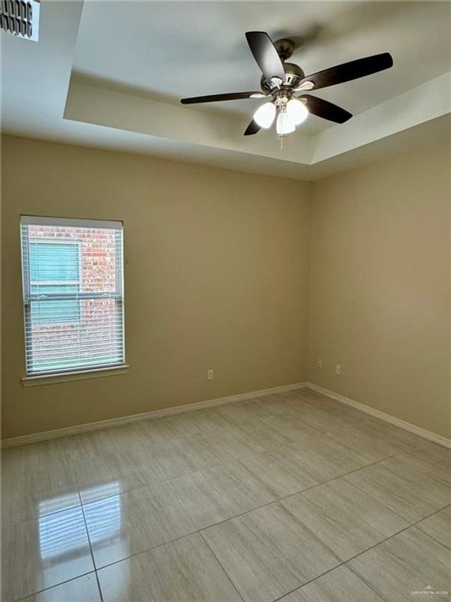 2nd bedroom with a tray ceiling, ceiling fan, and light tile patterned floors | Image 9