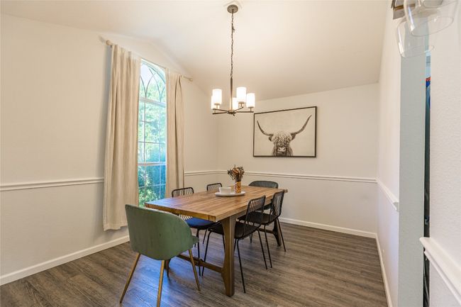 Dining space with a chandelier, dark wood-style flooring, vaulted ceiling, and baseboards | Image 6