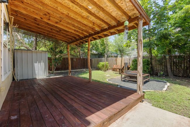 Backyard features a covered deck, fire pit, seating area, and storage shed. | Image 23