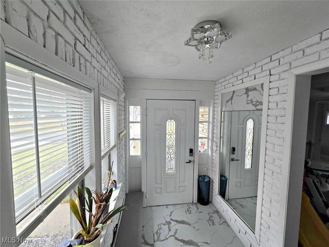 Entryway with marble finish floor, brick wall, and a textured ceiling | Image 12