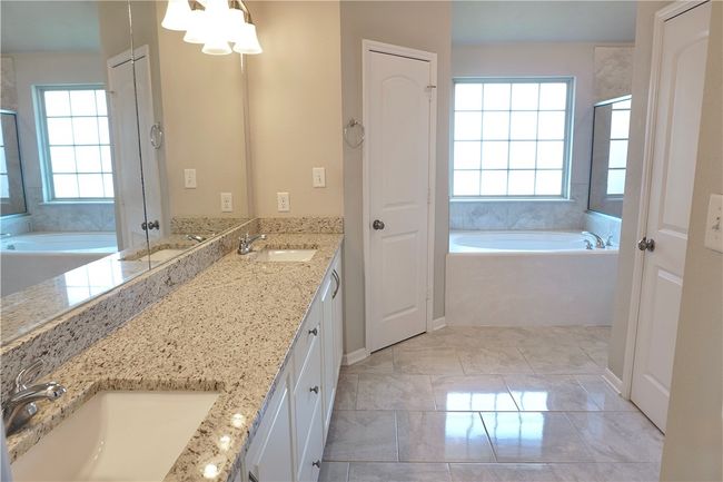 Full bath featuring plenty of natural light, double vanity, a bath, and marble look tiles | Image 11