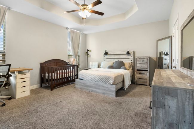 Carpeted bedroom featuring a tray ceiling, a desk, and ceiling fan | Image 10