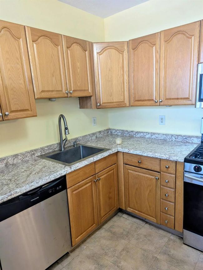 Kitchen with stainless steel appliances, light stone countertops, and light stone finish floors | Image 5