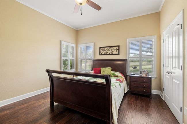 Bedroom with baseboards, a ceiling fan, dark wood finished floors, and crown molding | Image 11