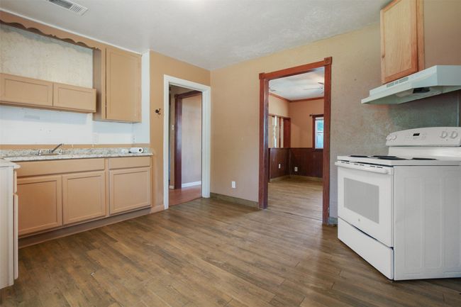 Kitchen featuring light countertops, under cabinet range hood, dark wood-type flooring, visible vents, and white electric range oven | Image 6