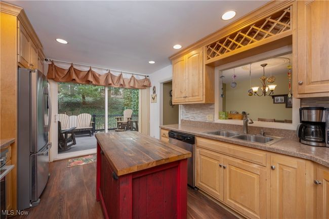 Kitchen with dark wood-style flooring, stainless steel appliances, butcher block counters, a kitchen island, and a sink | Image 21