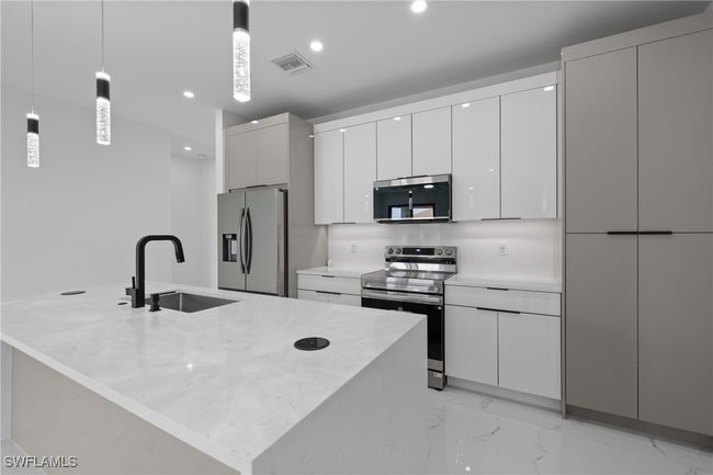Kitchen featuring stainless steel appliances, a sink, modern cabinets, recessed lighting, and decorative light fixtures | Image 9