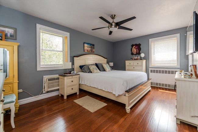 Bedroom featuring radiator, multiple windows, and dark wood-type flooring | Image 11