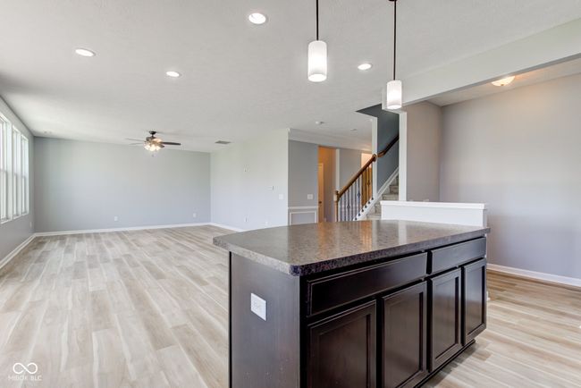 kitchen with a ceiling fan, light wood-style floors, recessed lighting, dark countertops, and pendant lighting | Image 8