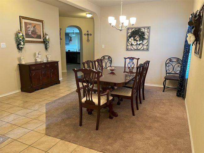 Dining space with light tile patterned floors and a chandelier | Image 9
