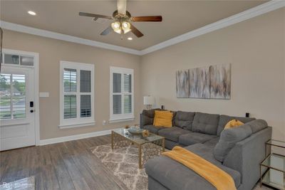 Living room with crown molding, wood-type flooring, and ceiling fan | Image 3