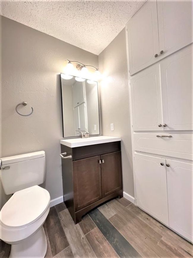 Bathroom featuring wood finished floors, toilet, a textured ceiling, vanity, and baseboards | Image 9