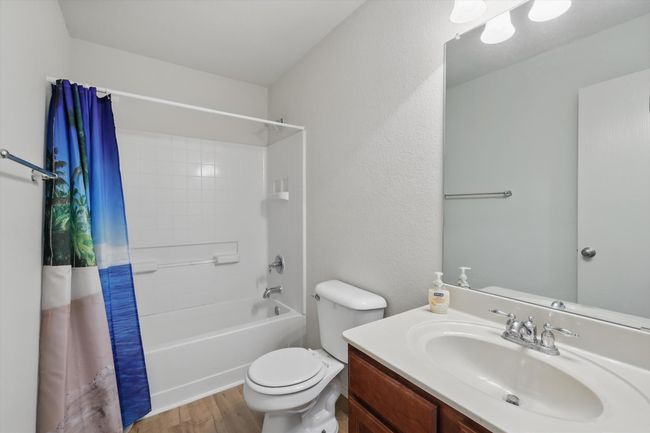 Full bath featuring wood finished floors, toilet, vanity, and shower / bath combo | Image 24