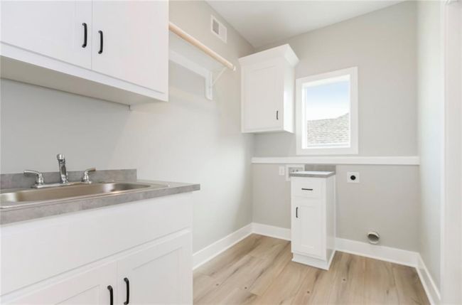 Washroom featuring electric dryer hookup, light wood-style flooring, cabinet space, and baseboards | Image 11