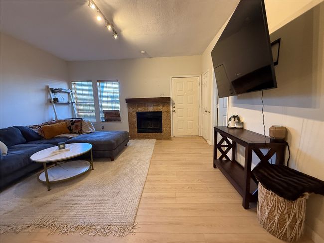 Living area featuring light wood-type flooring, a fireplace, and a textured ceiling | Image 6