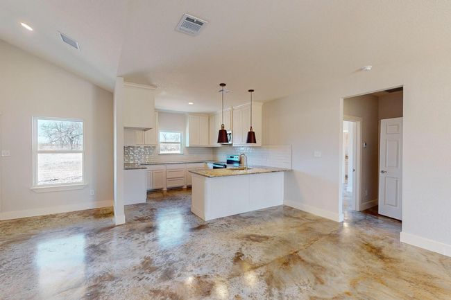 Kitchen featuring a peninsula, tasteful backsplash, concrete flooring, appliances with stainless steel finishes, and light stone countertops | Image 13