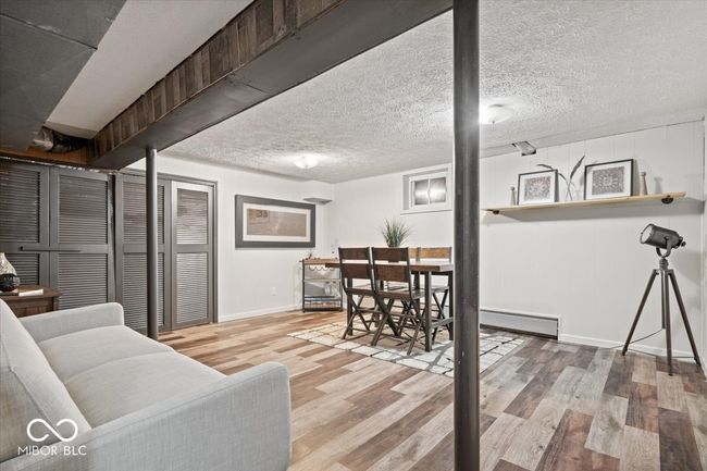 living area with baseboards, wood finished floors, a textured ceiling, and a baseboard radiator | Image 26