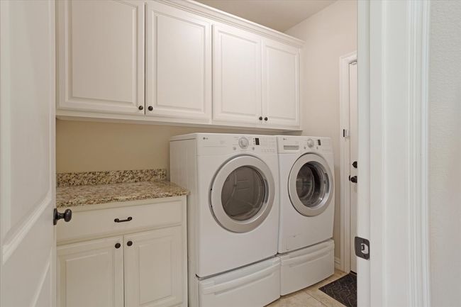Washroom with cabinet space, independent washer and dryer, and light tile patterned floors | Image 11