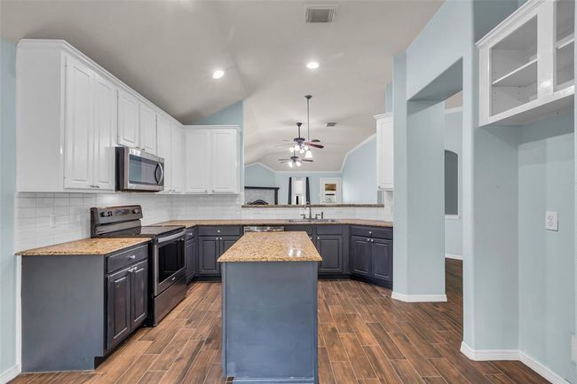 Kitchen features plenty of cabinets, granite counters, stainless appliances, prep island, and breakfast area. | Image 9