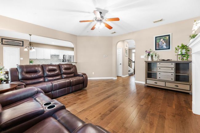 Living room with arched walkways, a ceiling fan, hardwood / wood-style flooring, baseboards, and stairs | Image 8