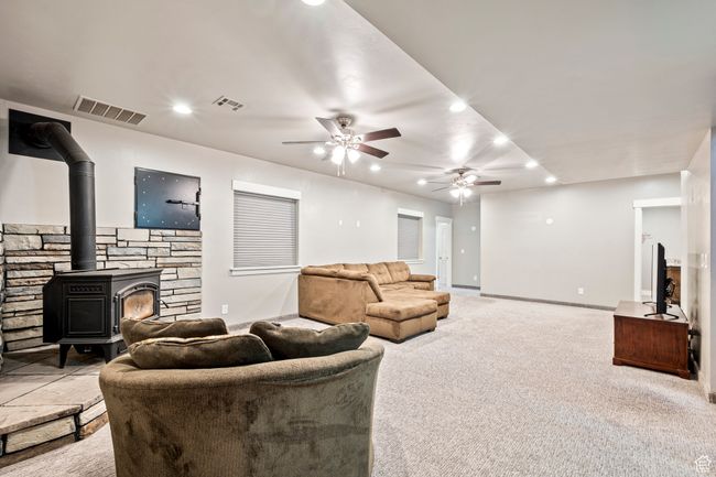 Living room featuring carpet, a wood stove, a ceiling fan, and visible vents | Image 38