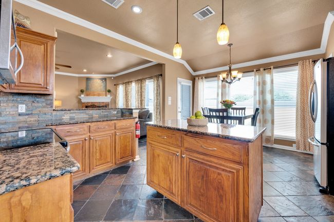 Kitchen with stainless steel appliances, stone tile flooring, ornamental molding, a chandelier, and decorative backsplash | Image 12