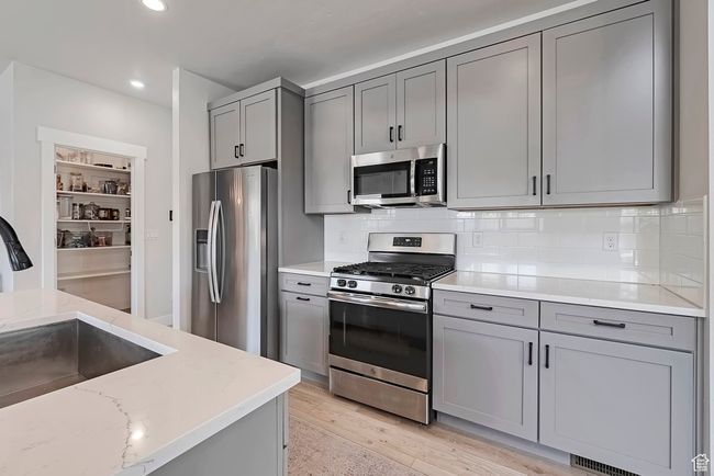 Kitchen with appliances with stainless steel finishes, gray cabinetry, a sink, tasteful backsplash, and recessed lighting | Image 7