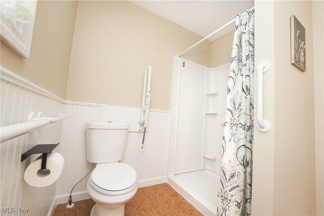 Full bathroom with curtained shower, wood finished floors, toilet, and baseboards | Image 19
