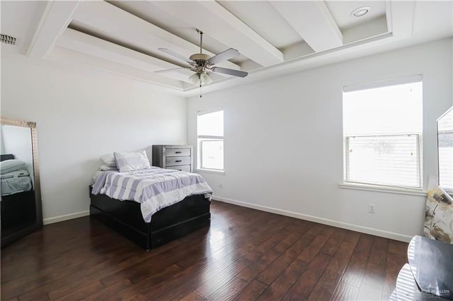 Bedroom with baseboards, a tray ceiling, dark wood finished floors, and beamed ceiling | Image 17